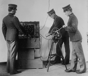 Three soldiers take a long paper feed from a wireless machine.