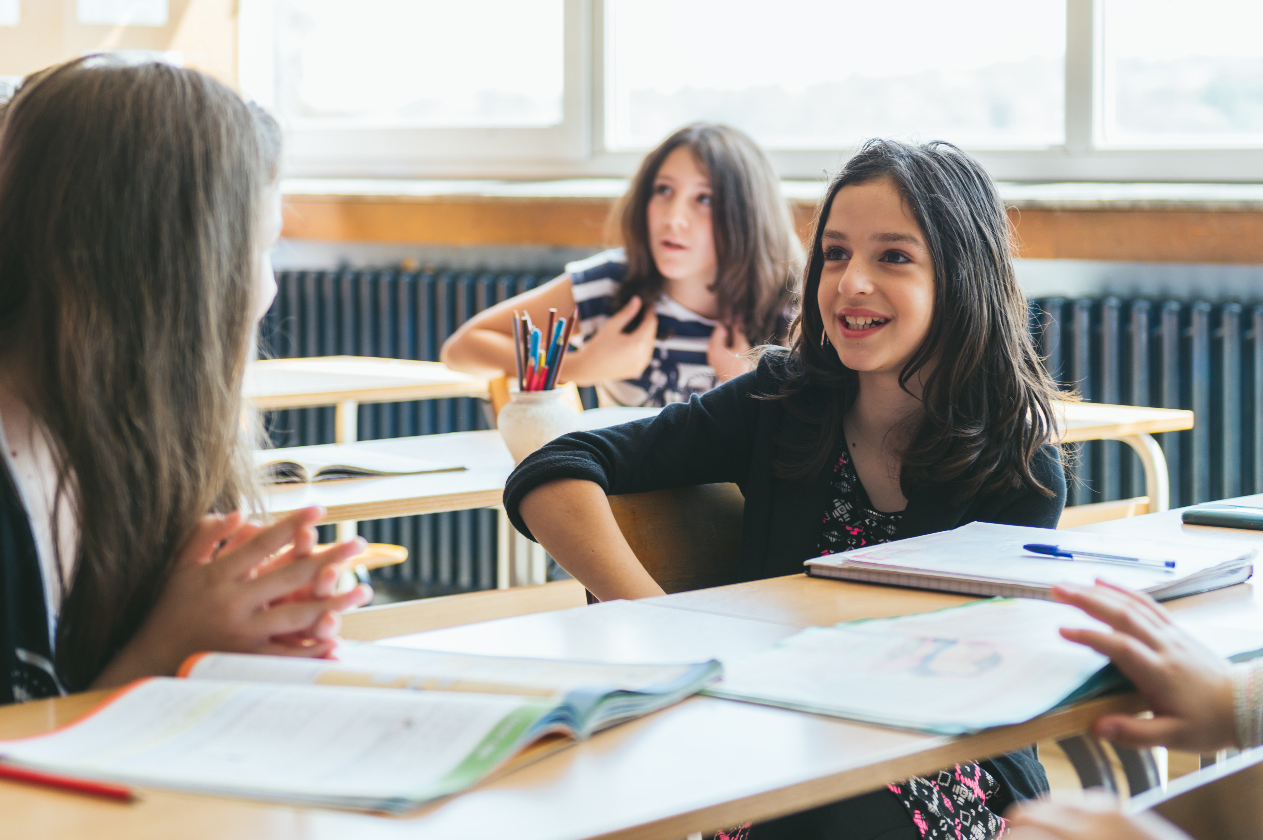 Elementary students at desks talking with each other.