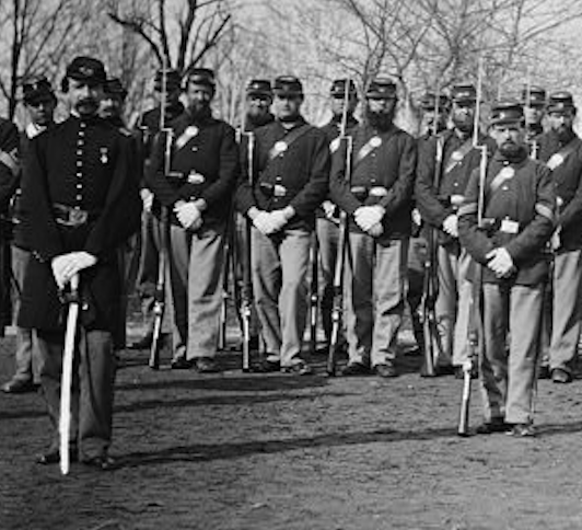 Soldiers of the Veterans Reserve Corps stand at parade rest in a long line. Soldiers wounded or ill from service manned Washington forts.