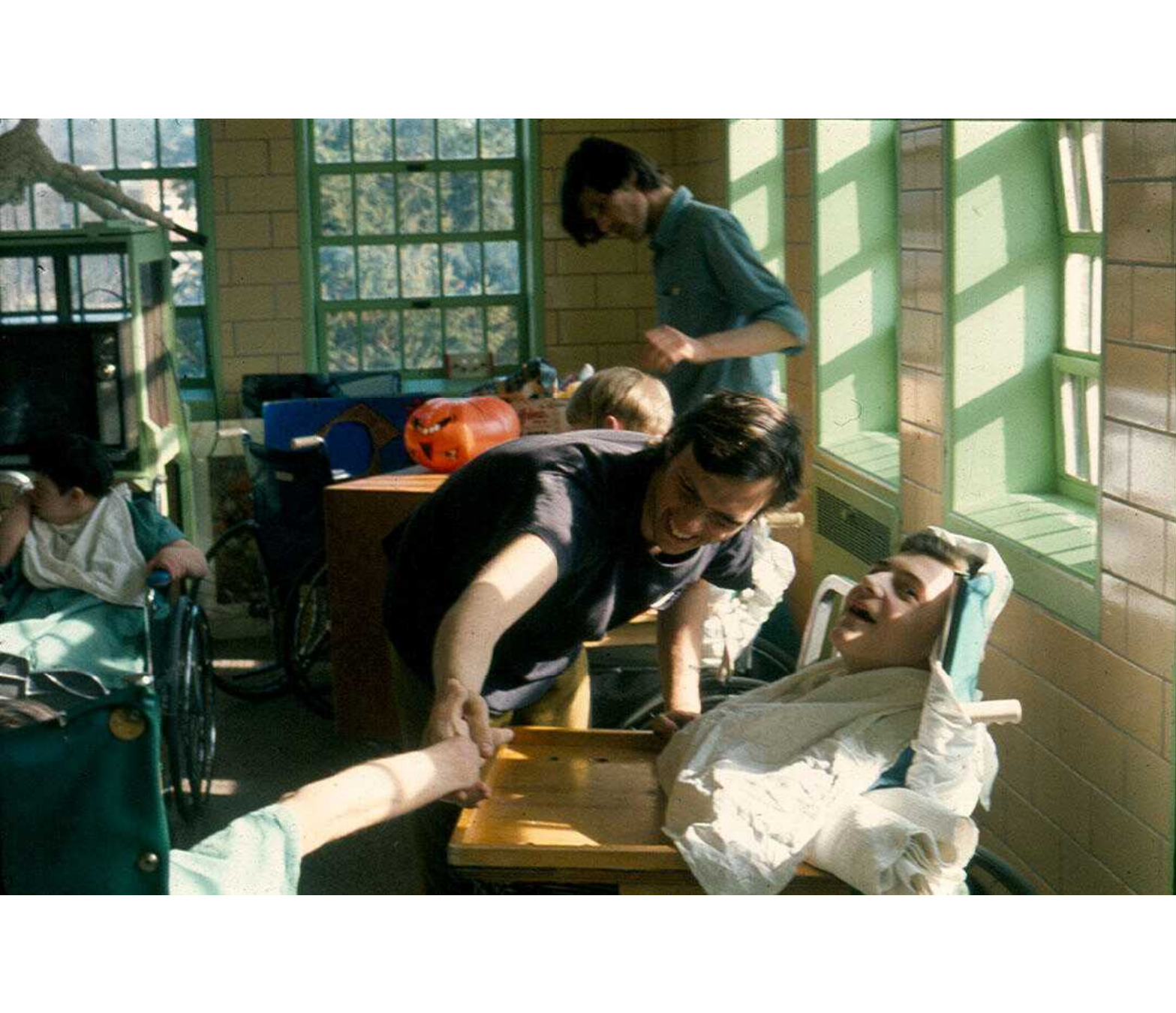 Workers at Belchertown State School help patients in wheelchairs.