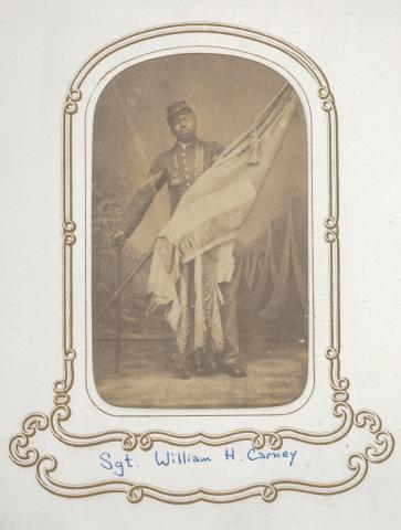 William Carney holding the flag he carried at Fort Wagner. In his other hand, Carney holds a cane. 