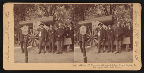 Officers and veterans, wearing uniforms, lounge next to a large cannon, Solders' Home, Dayton, Ohio. 