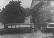 Buses with windows painted over, staff stand by open back door