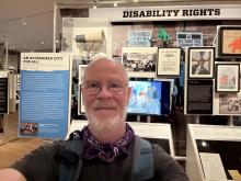 Emerging America's Rich Cairn selfie in front of the Disability Rights exhibit at the Museum of the City of New York - items are in the online exhibit
