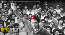 A dark-haired young man in a sweater holds up an arm as he speaks emphatically in front of a crowd of young men and women - Text reads RetroReport - How a 1968 Student Protest Fueled A Chicano Rights Movement. YouTube.