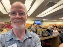 Selfie of a white man with glasses and a white beard in front of participants in a college classroom