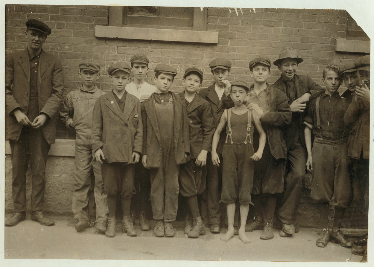 Child Laborers from 1911 (10 boys) pose in a line next to a man, no child taller than his shoulder