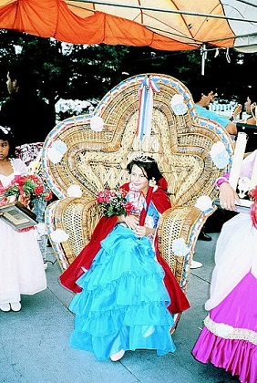15 year old girl in long ruffled blue gown sits on a throne-like chair