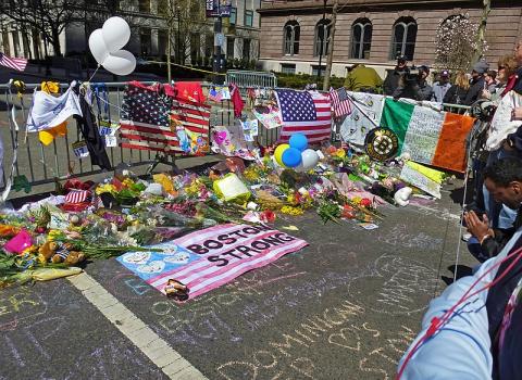 Homemade memorial from 2013 - Boston Strong with flags, flowers, and hundreds of sports and personal items displayed against a fence